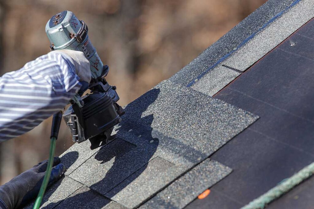 A roofer rolls a reflective coating across a clean low-slope roof beside prepared seams and flashing.